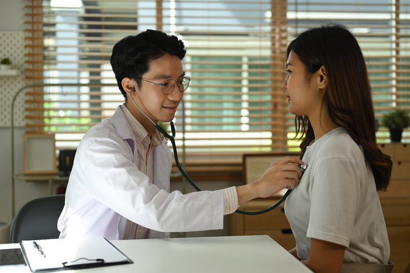 Doctor in white uniform using stethoscope checking heart lungs of female patient in hospital.prathanchorruangsak