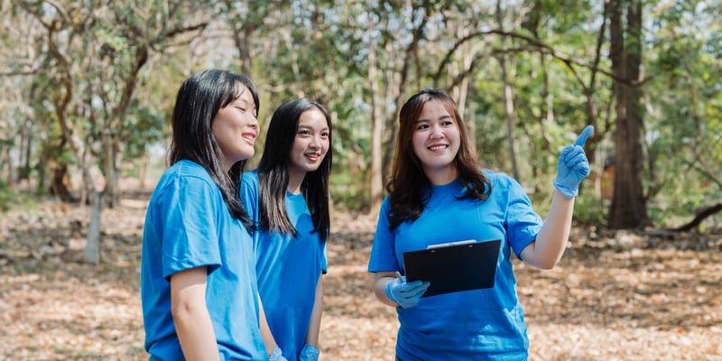 Smiling Volunteers Plan Cleanup in Lush Forestitchaznong