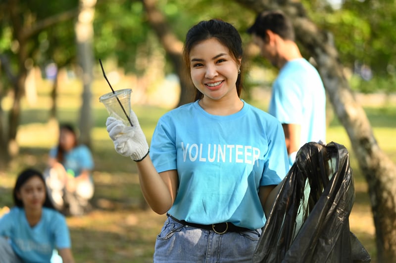 Positive female volunteer with garbage bag cleaning up the forest. Charity and ecology conceptprathanchorruangsak
