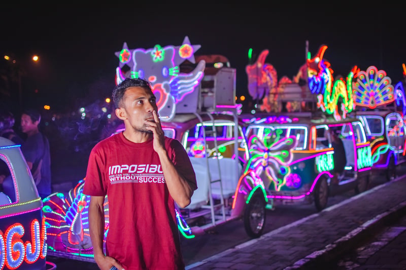 Indonesia man smoking cigarette in night with beautiful multi color cars in backgroundMelianChongQ