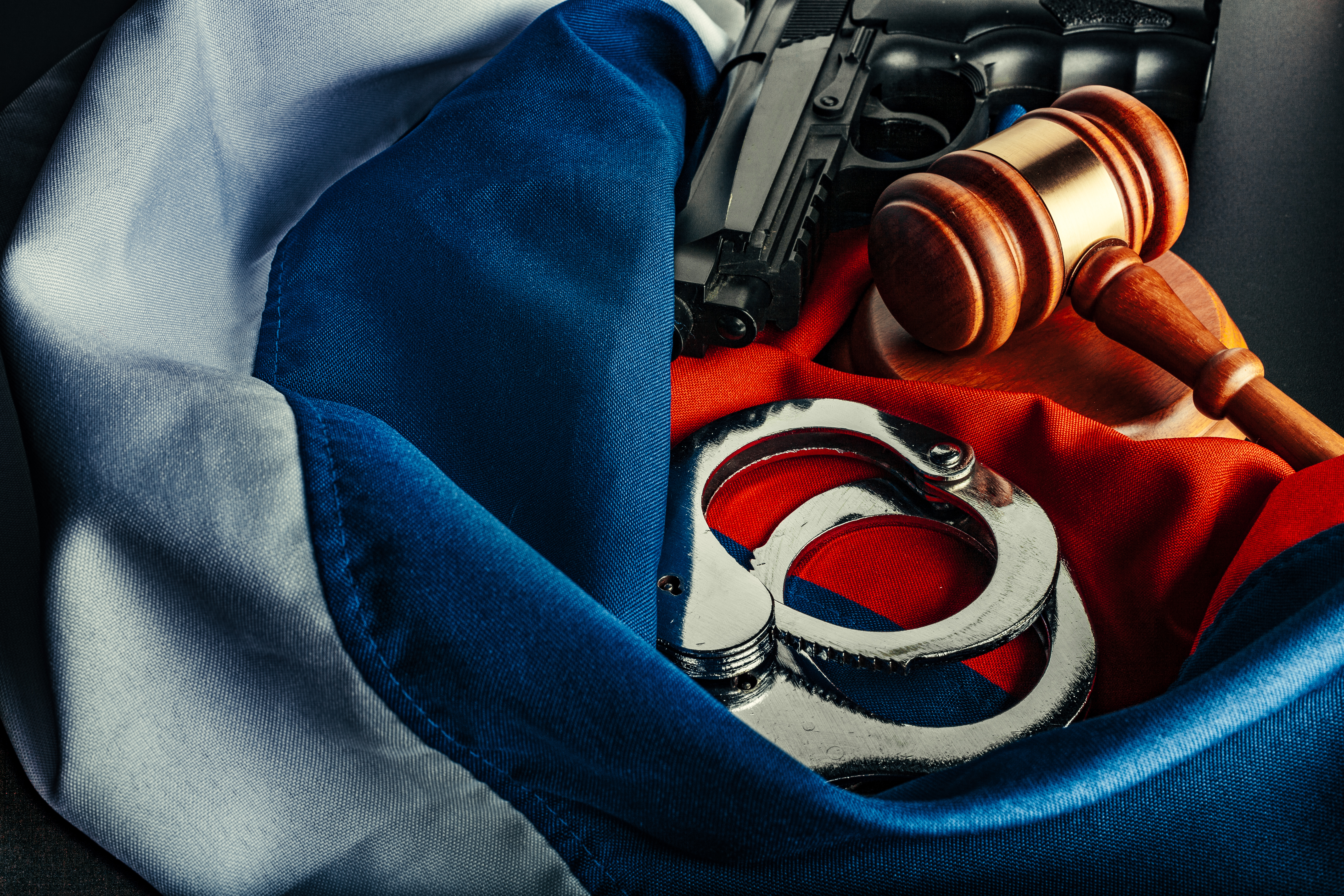Gavel, Handcuffs and Gun on a Flag Backdrop