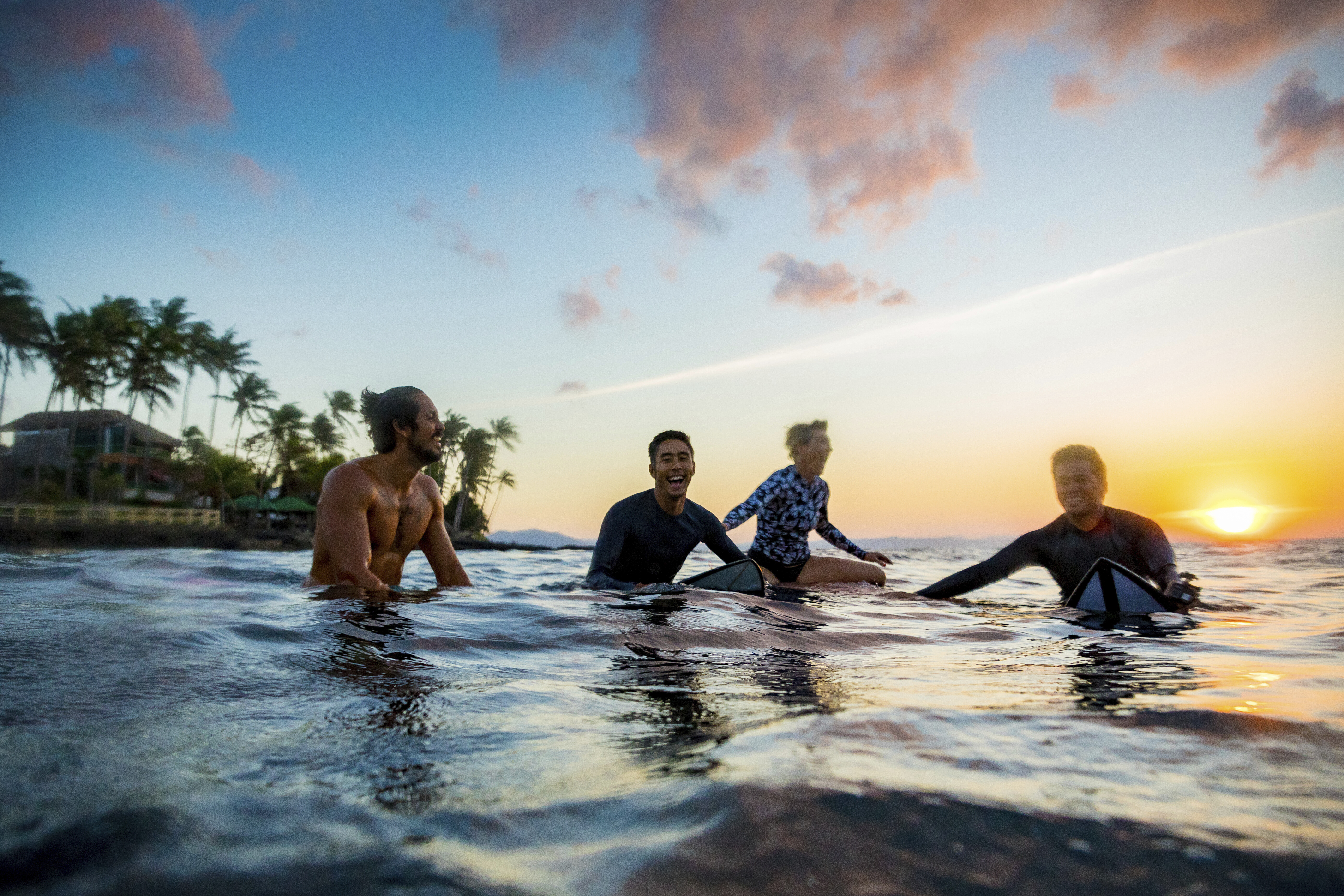 Surfers gliding in sea at sunset, Pagudpud, Ilocos Norte, Philippines