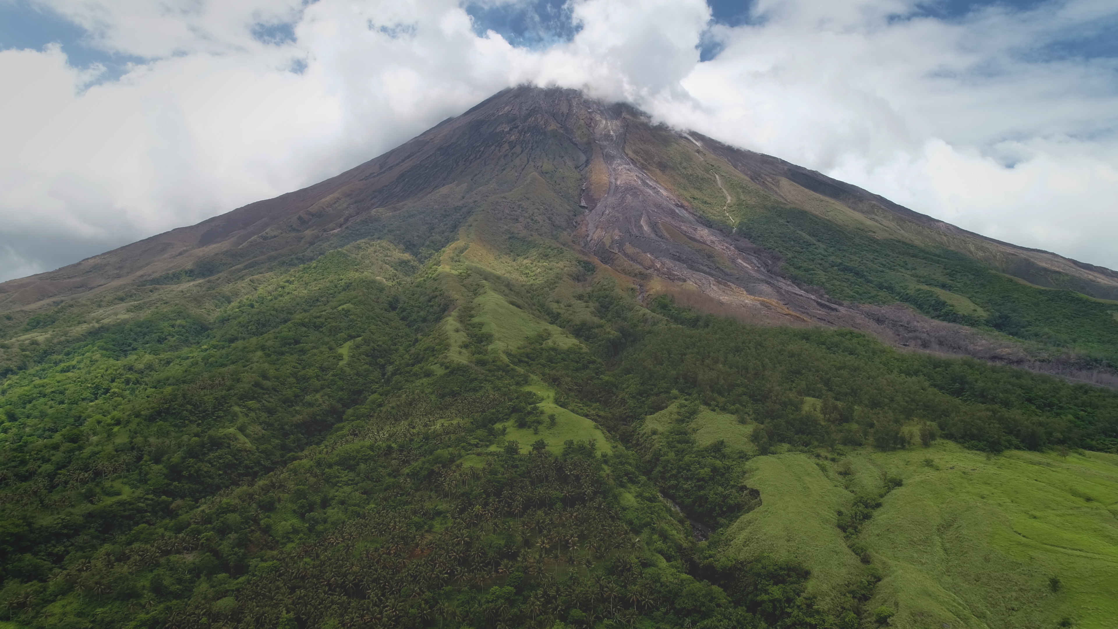 Closeup Philippines volcano top erupt clouds of haze aerial. Green grass mountain with hiking path