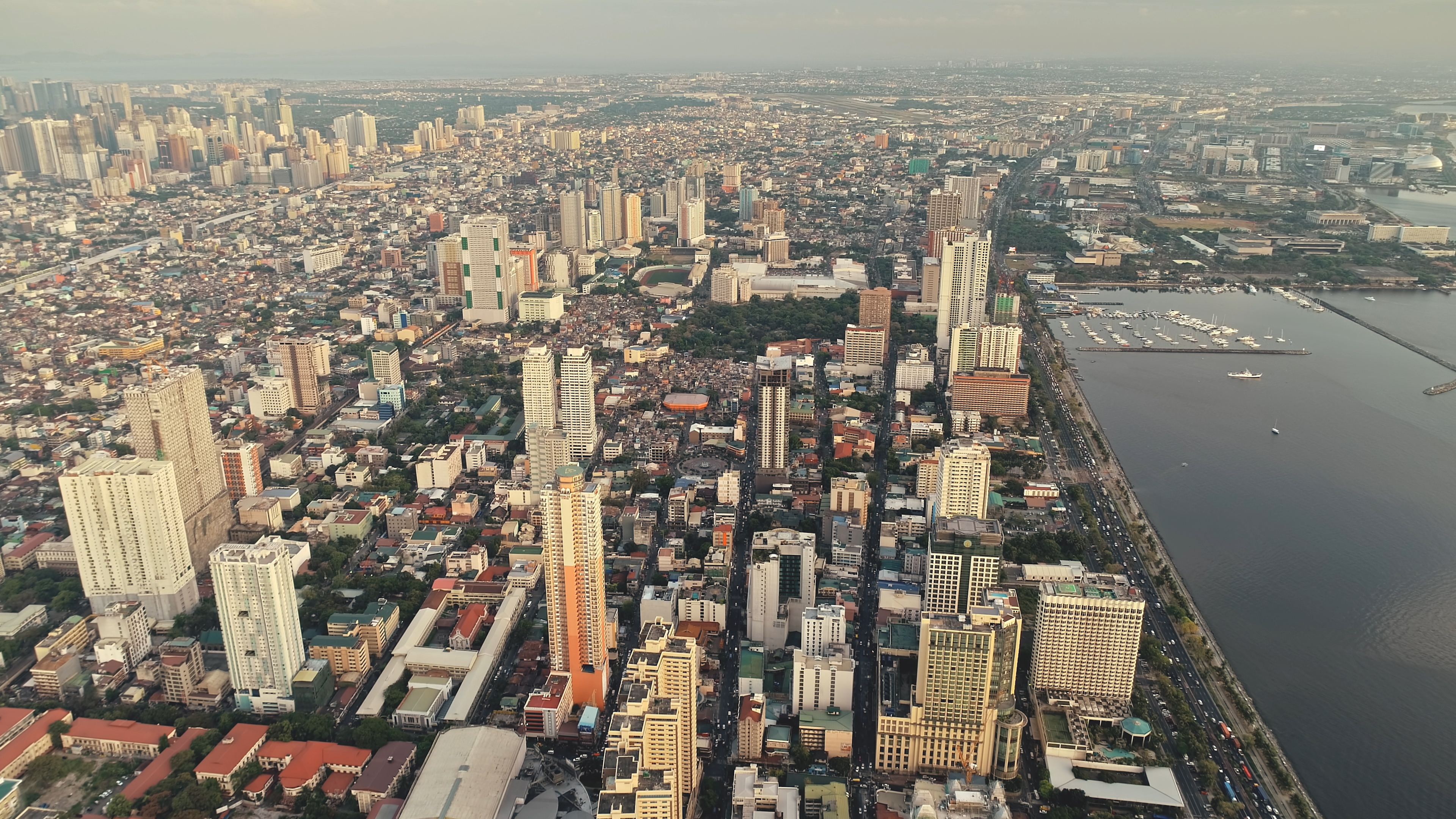 Metropolis port city of Manila at sea bay aerial view. Urban cityscape of streets and roads