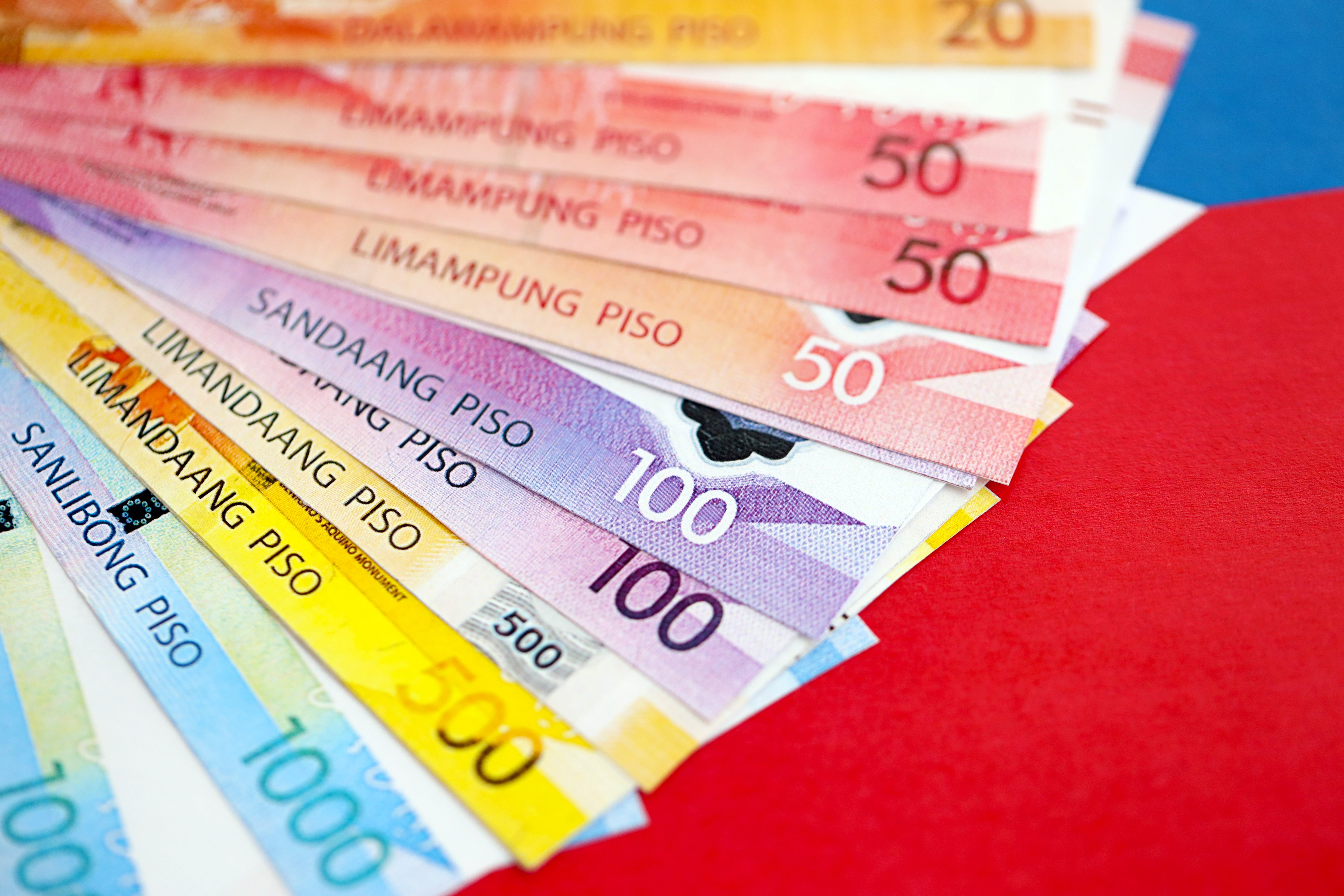 Close-up of Various Philippine Peso Banknotes Fan on Red Background