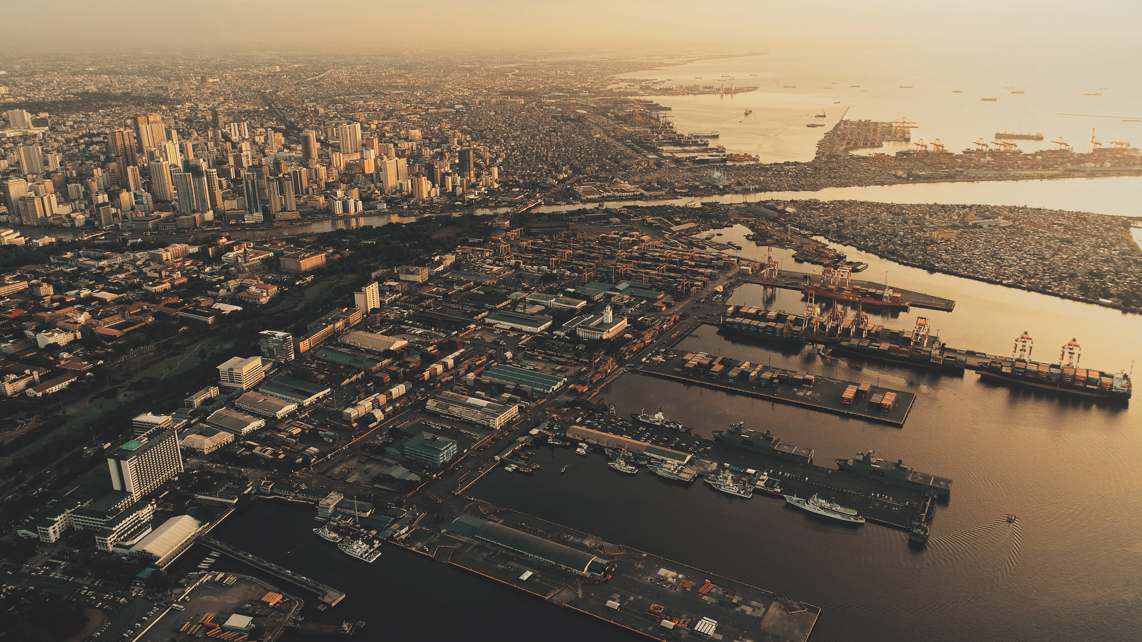 Sunset at metropolis port city Manila at ocean bay aerial. Sun light at marina with ships, boats