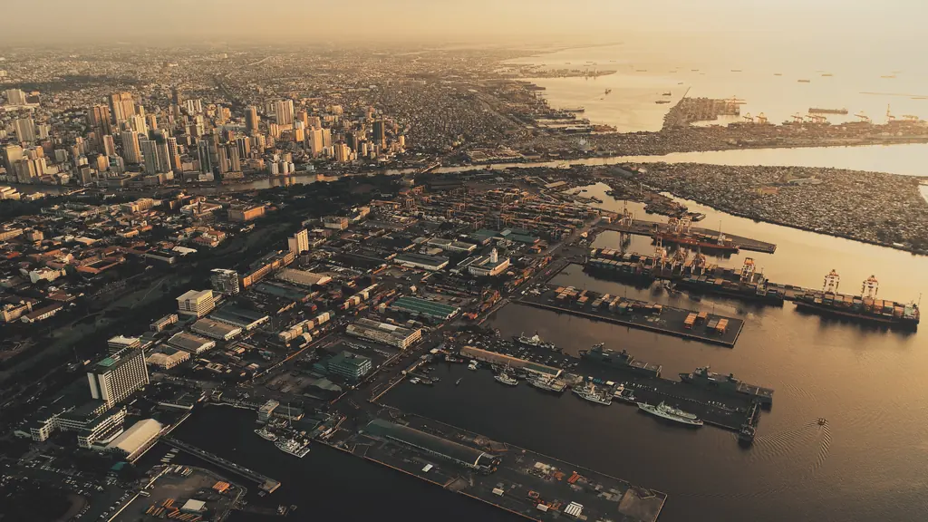 Sunset at metropolis port city Manila at ocean bay aerial. Sun light at marina with ships, boats