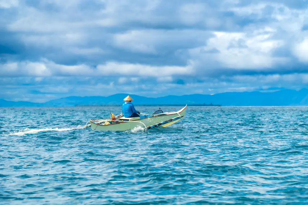 Filipino fisherman navigating the waters of siargao island, philippines