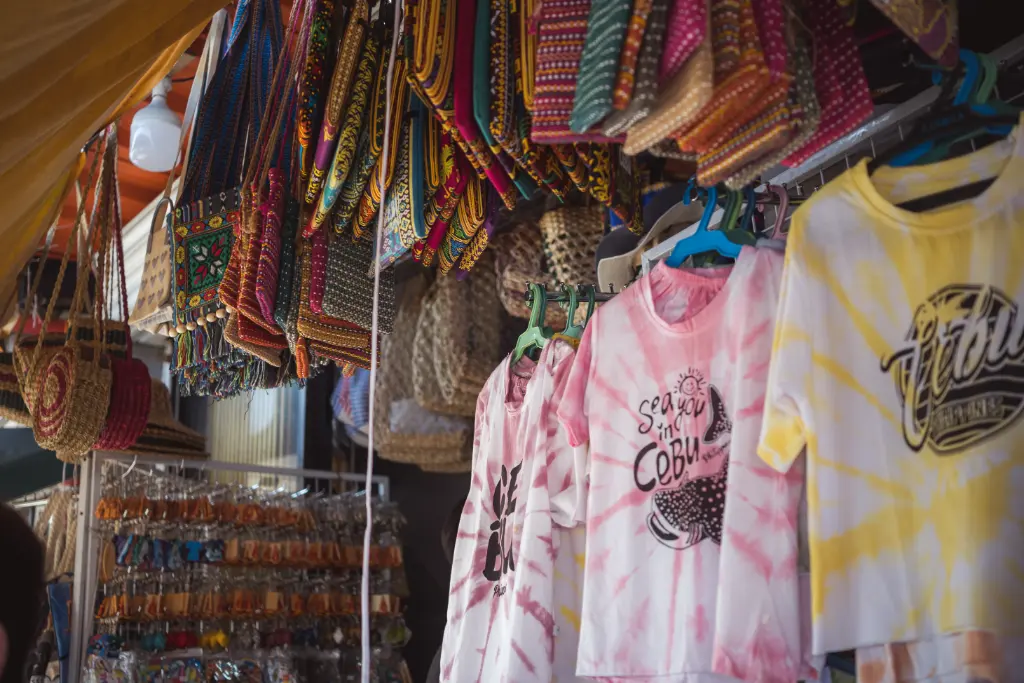 Vibrant display of colorful bags and t-shirts in a Cebu City market stall.