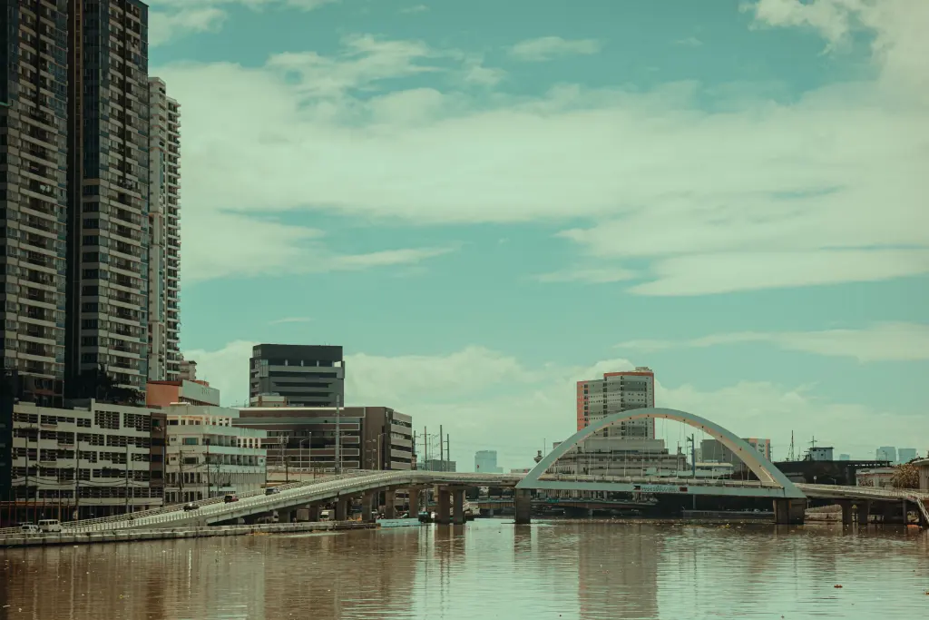 Scenic urban cityscape featuring a modern bridge and skyscrapers reflecting in calm waters.