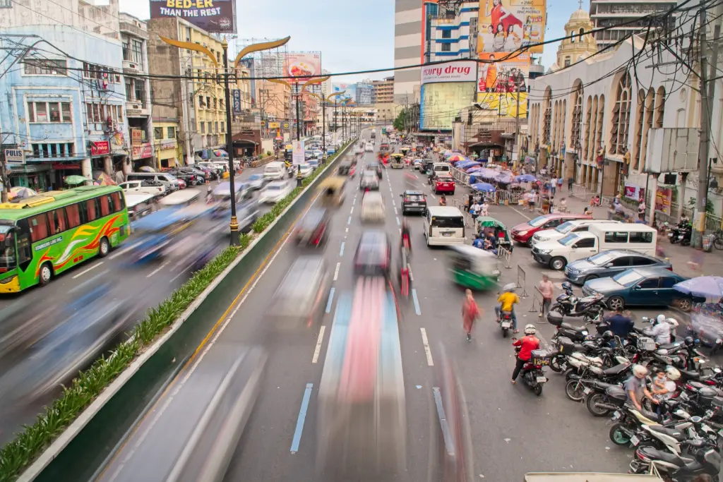 Vibrant daytime traffic in Manila city, showcasing bustling urban life and fast-moving vehicles.