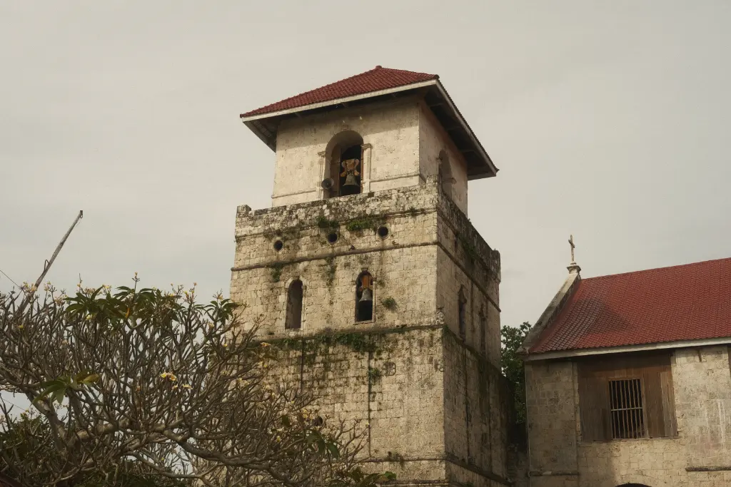 Rustic church tower set amidst lush vegetation in Bohol, Philippines, showcasing Spanish colonial architecture.