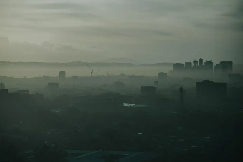 Moody urban landscape of Quezon City shrouded in mist at dawn, capturing a serene yet dramatic cityscape.