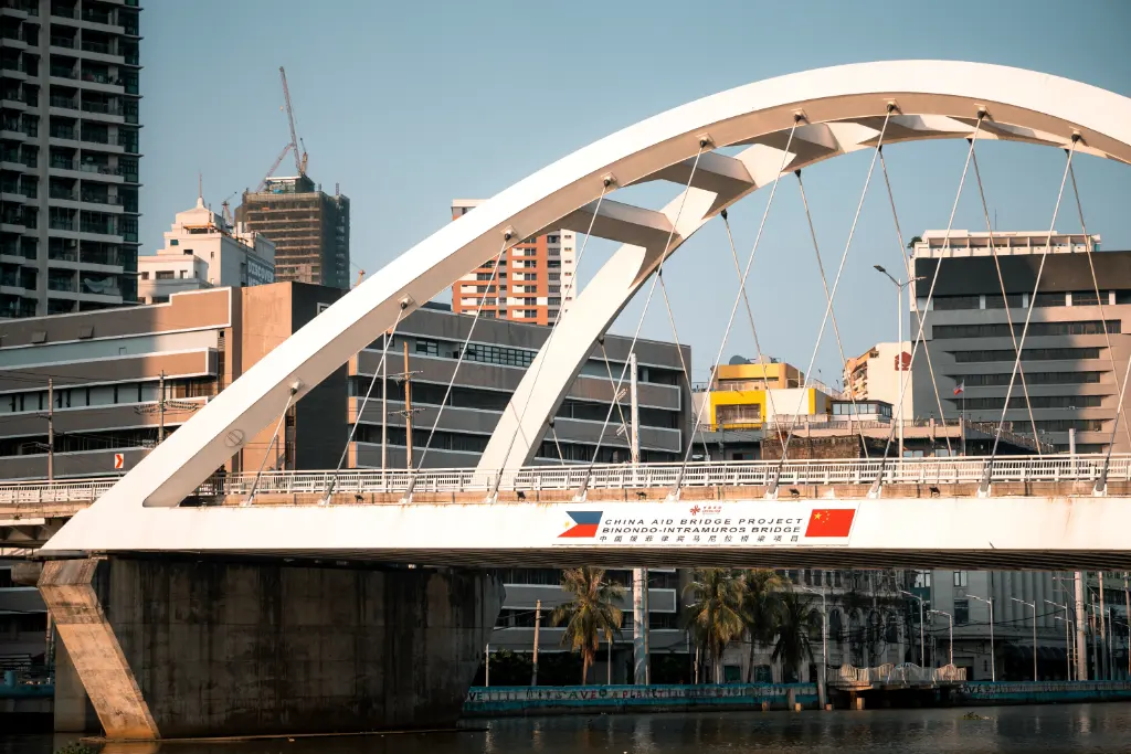 View of the Binondo-Intramuros Bridge in Manila, Philippines, with modern architecture backdrop.