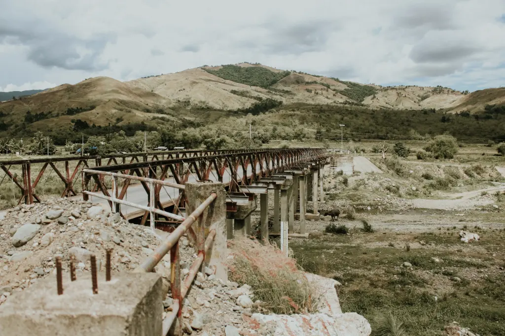 A scenic view of a rustic bridge set against the rolling hills of Carranglan, Philippines.