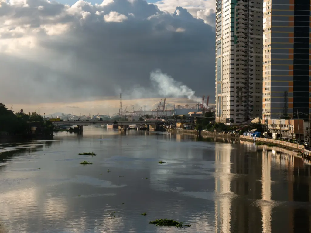 Aerial view of an urban river with high-rise buildings and industrial skyline at sunrise.
