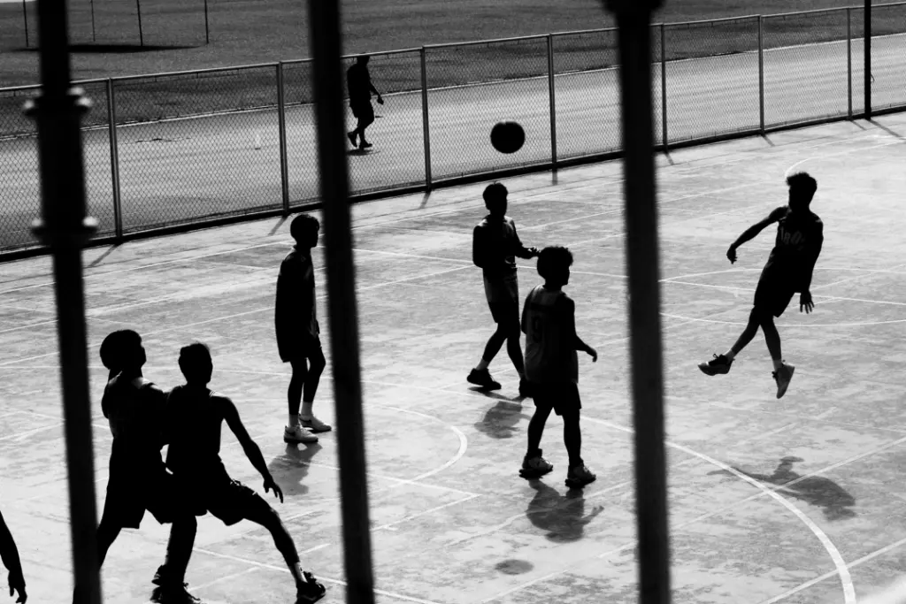 Black and white silhouette of teenagers playing basketball on an outdoor court in Marikina, Philippines.