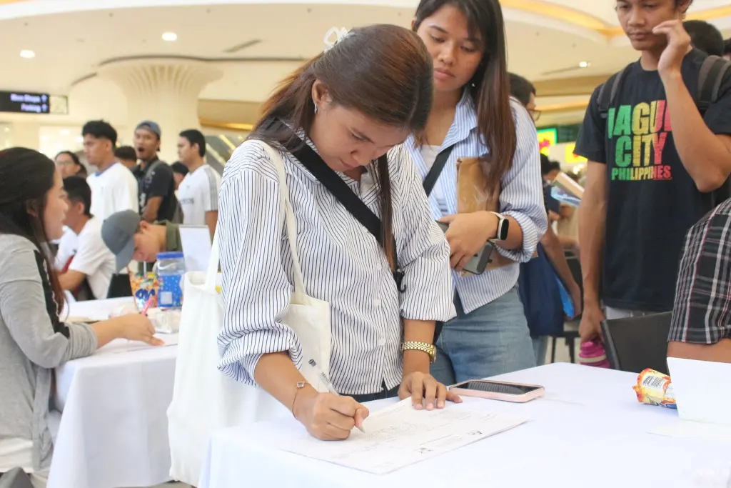 Rosalinda Shah fills out form during the PWD Job Fair 2026 held in Camarines Sur, joining other PWD applicants in seeking inclusive employment opportunities. (NFrilles /PIA5/CamSur)