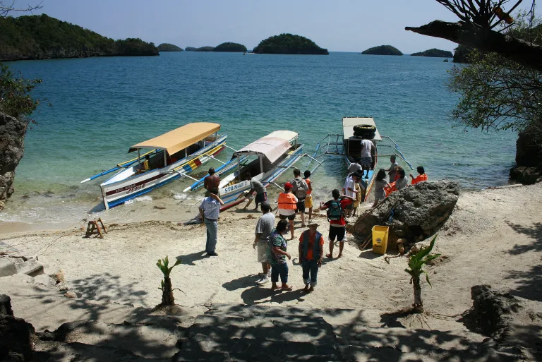 Auslegerboote und anlandende Besucher am Strand von Governor’s Island
