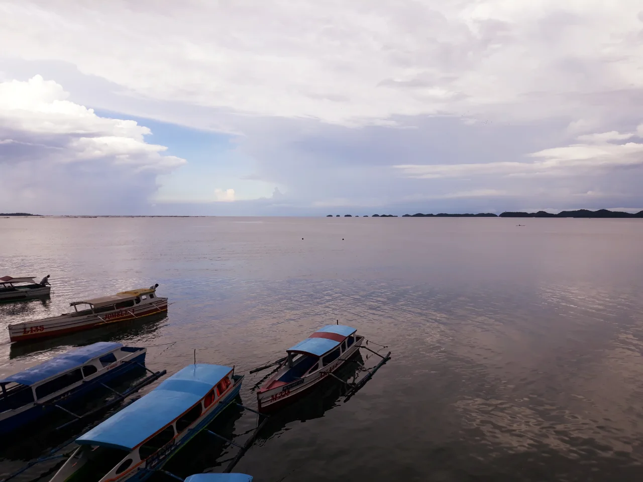 Auslegerboote in der Lucap Bay, dahinter die Hundred Islands am Horizont