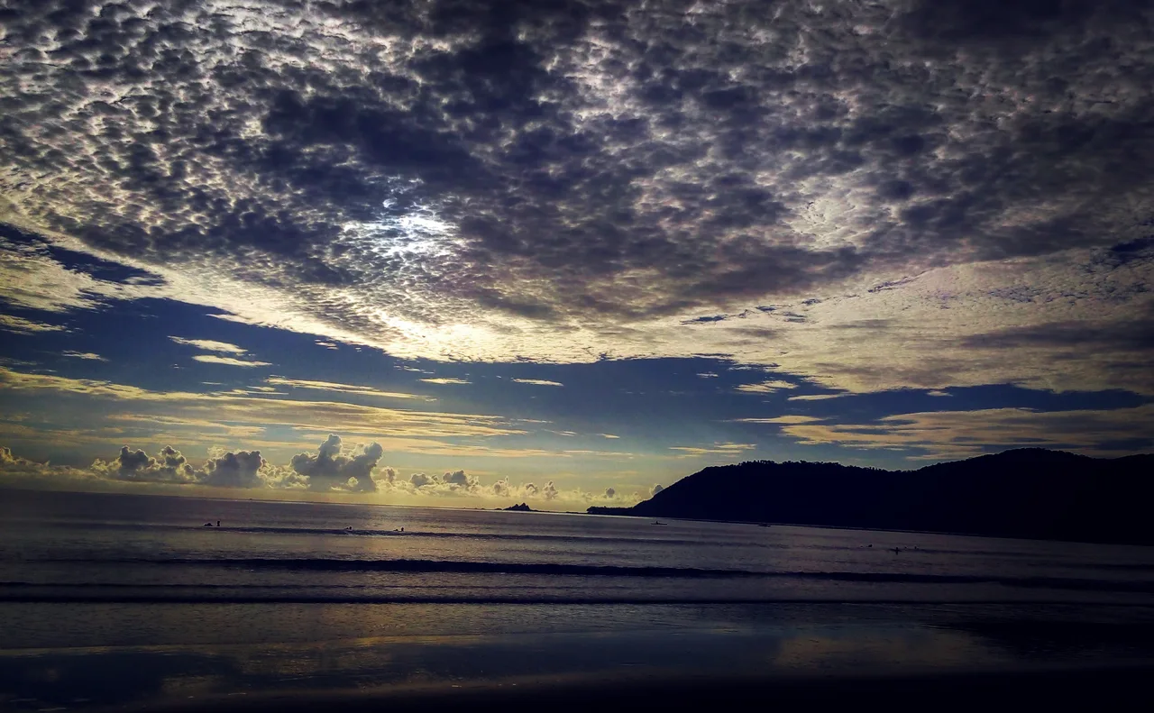 Wellen am dunklen Strand von Sabang in Baler unter einer Wolkendecke