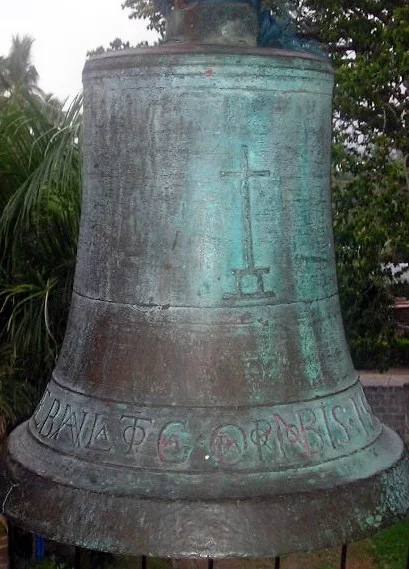 Grünlich patinierte Glocke mit Kreuz und umlaufender Inschrift