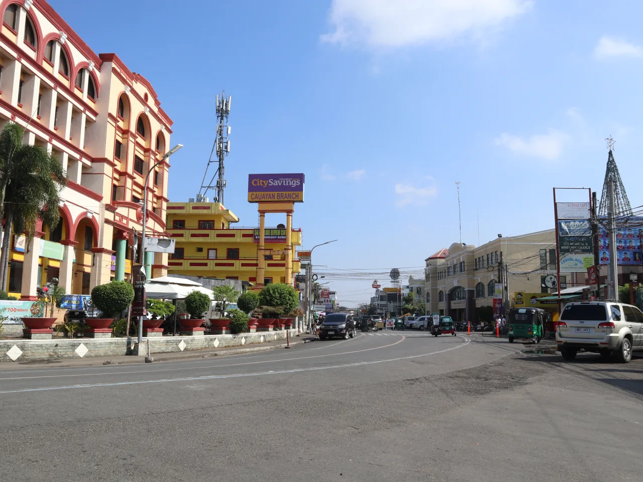 Rizal Street in Cauayan mit Geschäften, Fahrzeugen und Tricycles