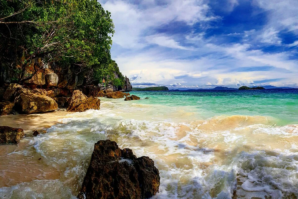 Abgelegener Strand mit hellem Sand und vorgelagerten Felsen auf Dinagat Island