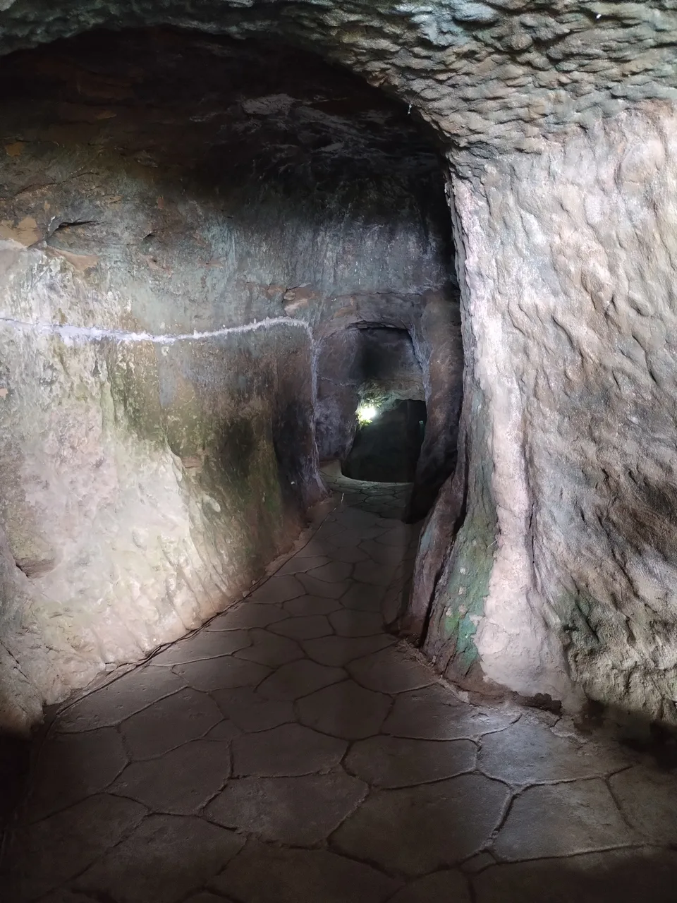 Beleuchteter schmaler Gang mit unregelmäßigen Felswänden im Ilagan Japanese Tunnel