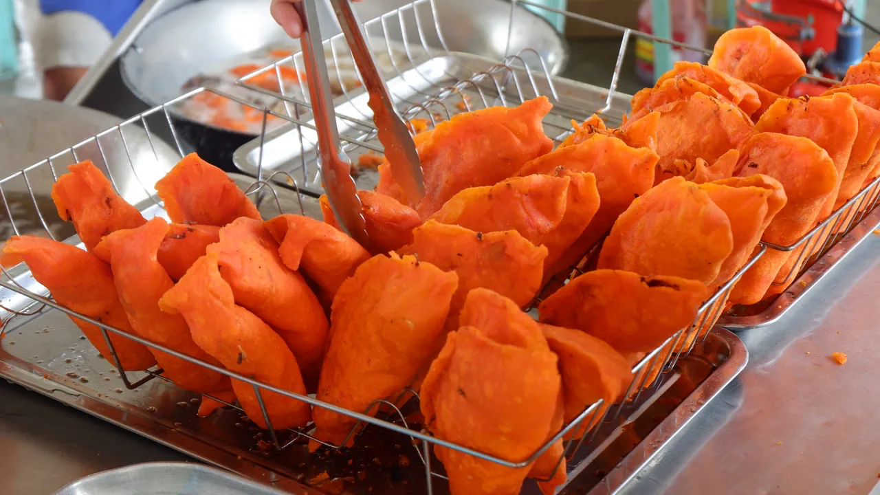 Orangefarbene Ilocos-Empanadas auf einem Abtropfgitter in Batac