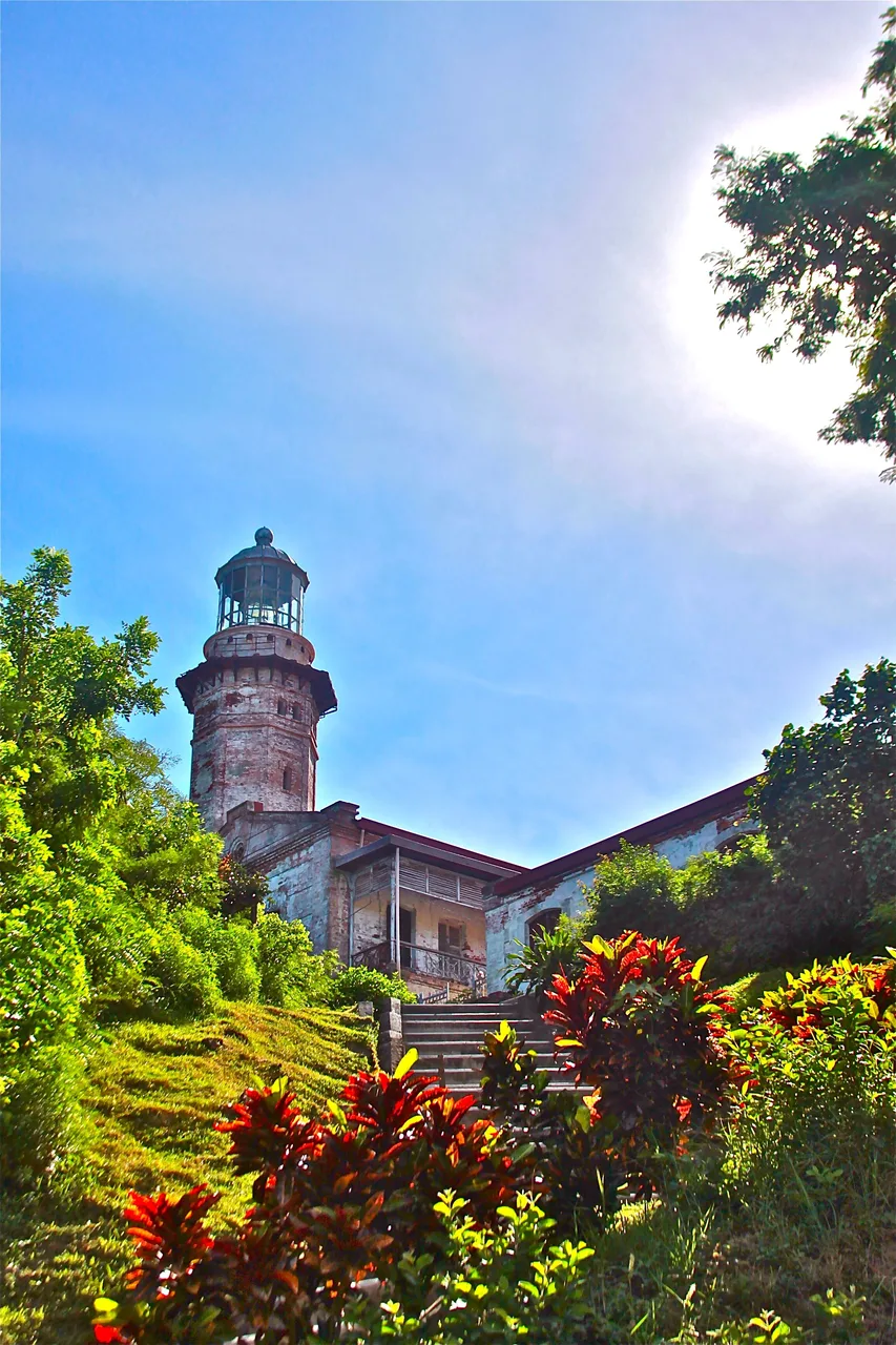 Cape-Bojeador-Leuchtturm mit Treppe, Mauerwerk und Vegetation unter blauem Himmel
