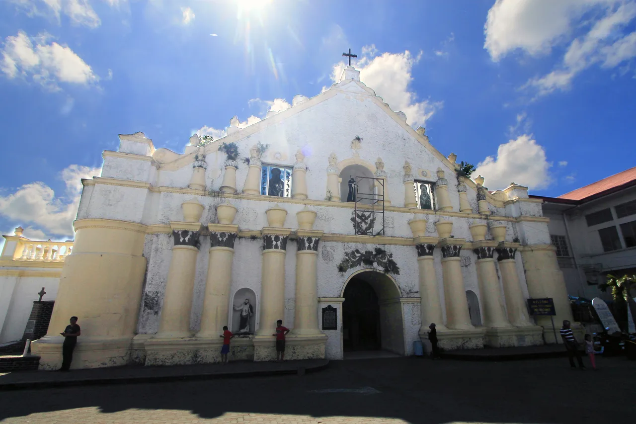 Helle Fassade der St.-William-Kathedrale in Laoag mit einzelnen Besuchern