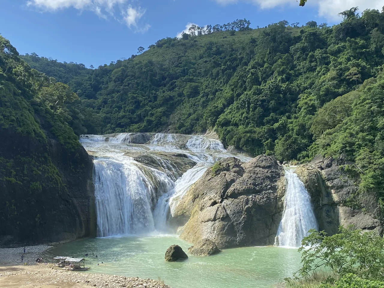 Pinsal Falls mit mehreren Wasserläufen über Felsen und einem Becken vor bewaldeten Hängen