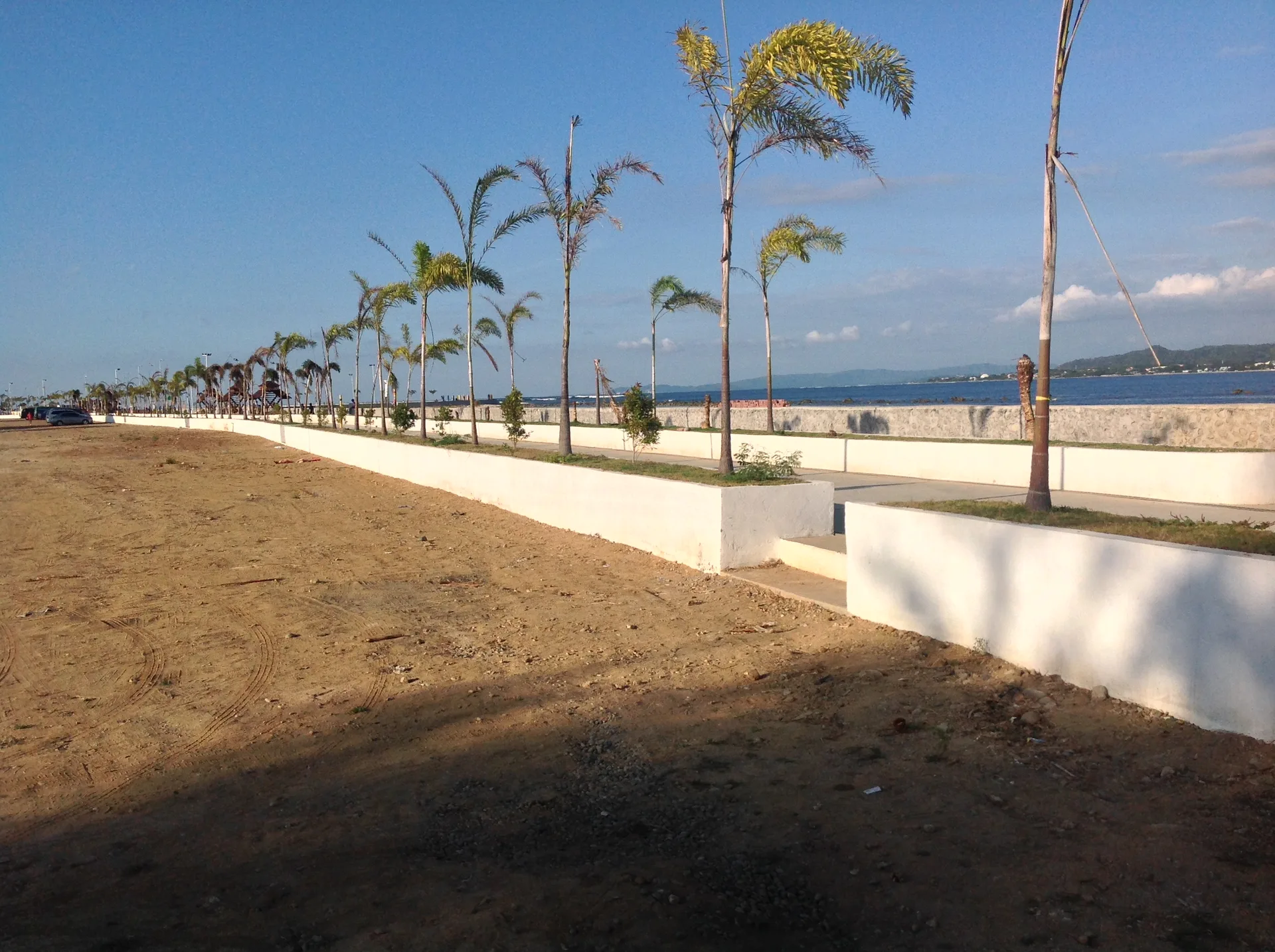 Palmen und Promenade am Poro Point Baywalk mit Blick über die Bucht