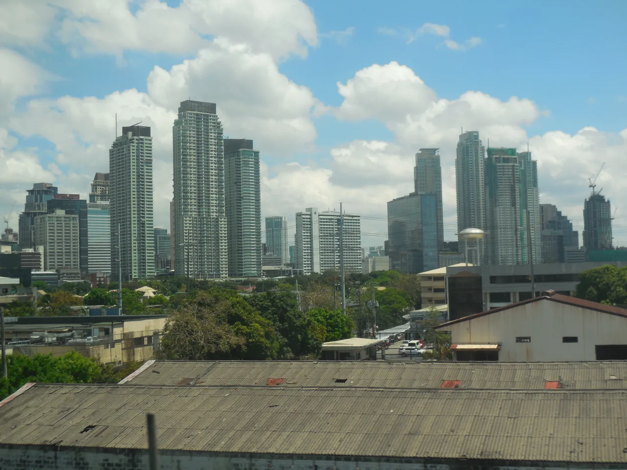 Hochhäuser von Makati hinter niedrigeren Dächern, vom Skyway aus gesehen