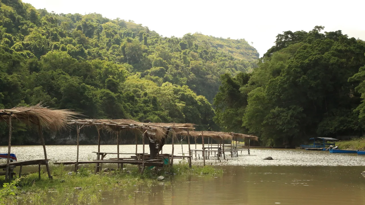 Pinacanauan River zwischen bewachsenen Hängen mit einfachen Unterständen am Ufer