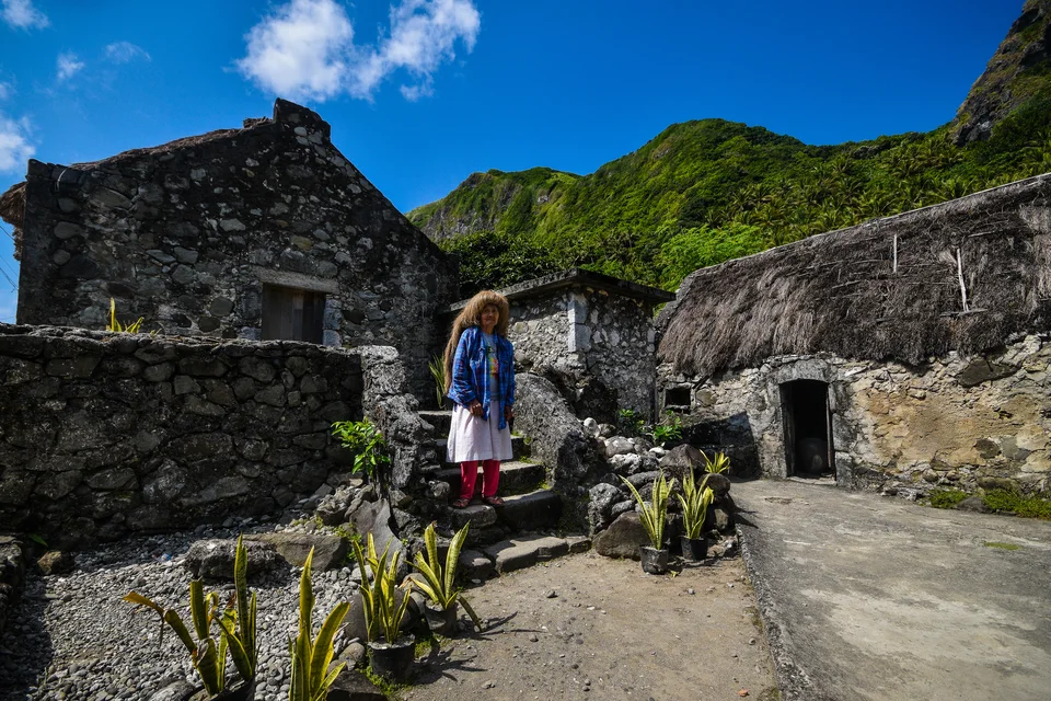 Traditionelle Steinhäuser mit grasgedeckten Dächern in Chavayan und eine Person auf einer Steintreppe