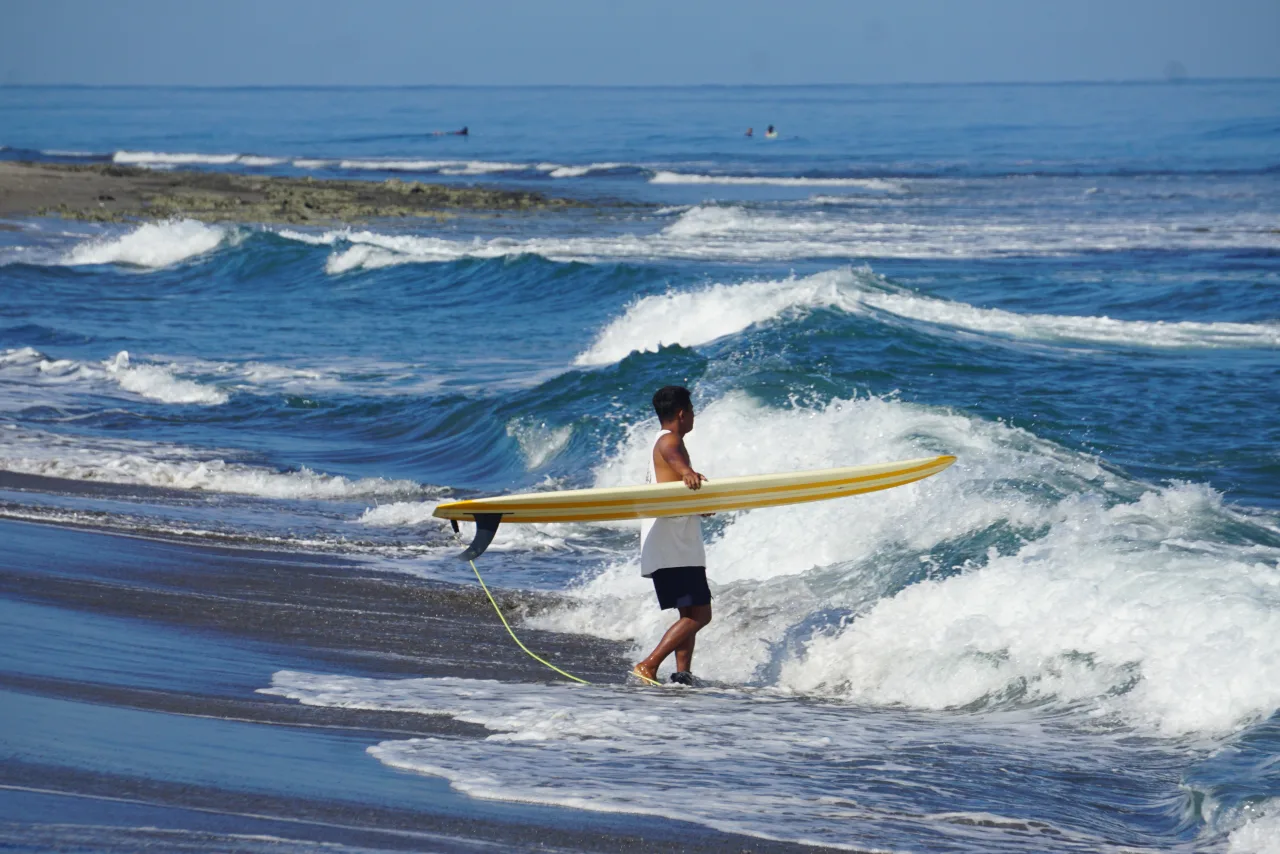 Surfer mit gelbem Board am Strand von Urbiztondo in San Juan
