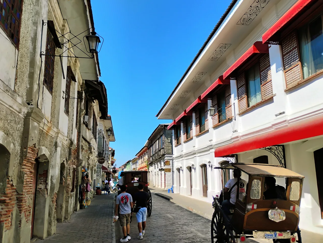 Calle Crisologo mit historischen Häuserfronten, Fußgängern und Pferdekutschen
