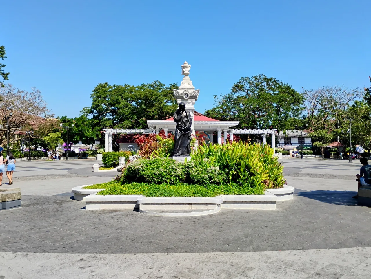 Denkmal auf der Plaza Burgos mit Blumenbeeten und Bäumen